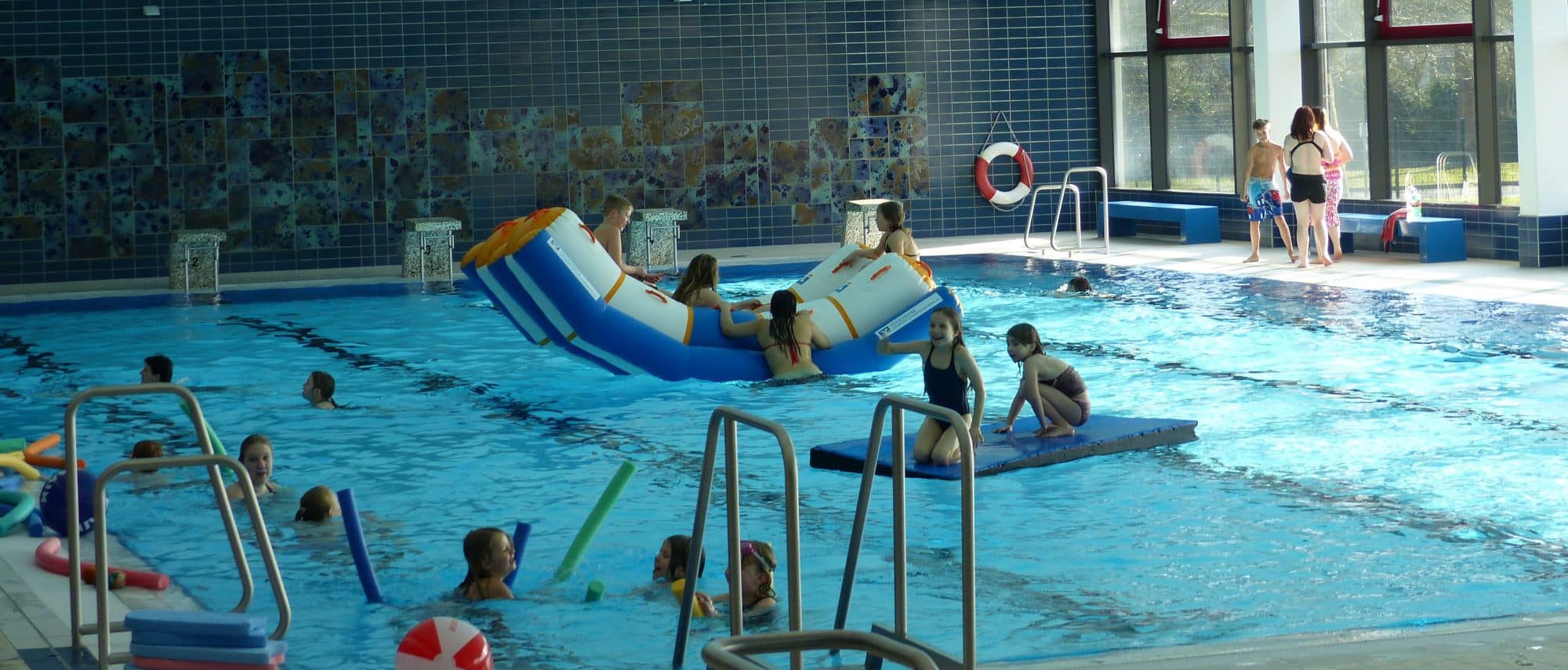 Innenaufnahme der LüBad-Schwimmhalle mit Becken, Fliesenwand und Spielbetrieb