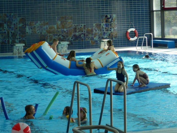 Innenaufnahme der LüBad-Schwimmhalle mit Becken, Fliesenwand und Spielbetrieb